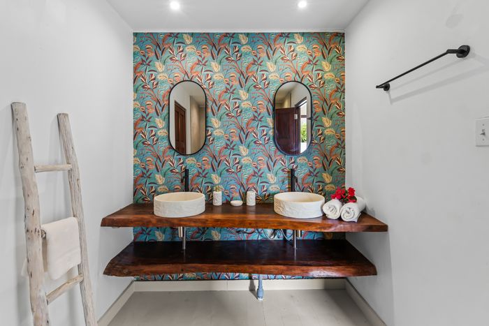 Bathroom with a double basin and colourful botanical wallpaper