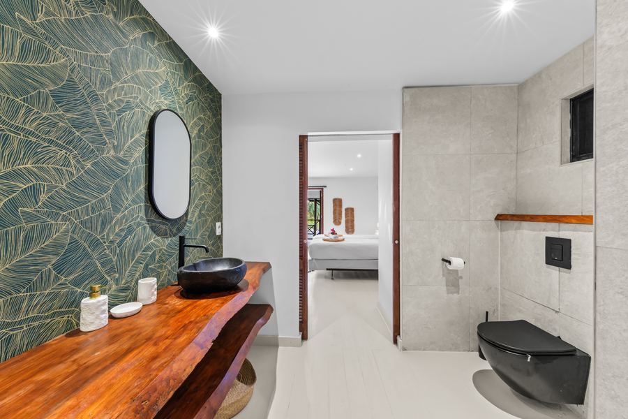 Badkamer met groen behang en doorkijk naar de slaapkamer