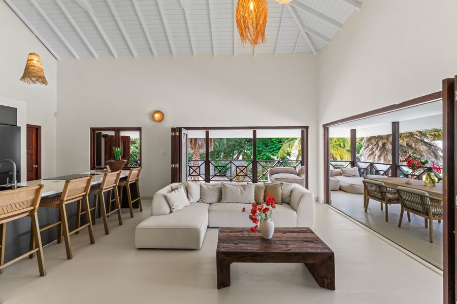 The living room under the tall white roof, looking through to the veranda